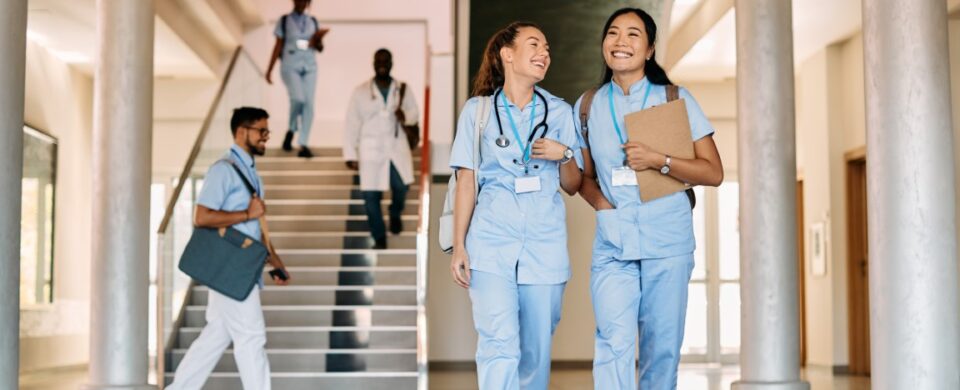 Happy female medical students walking through hall